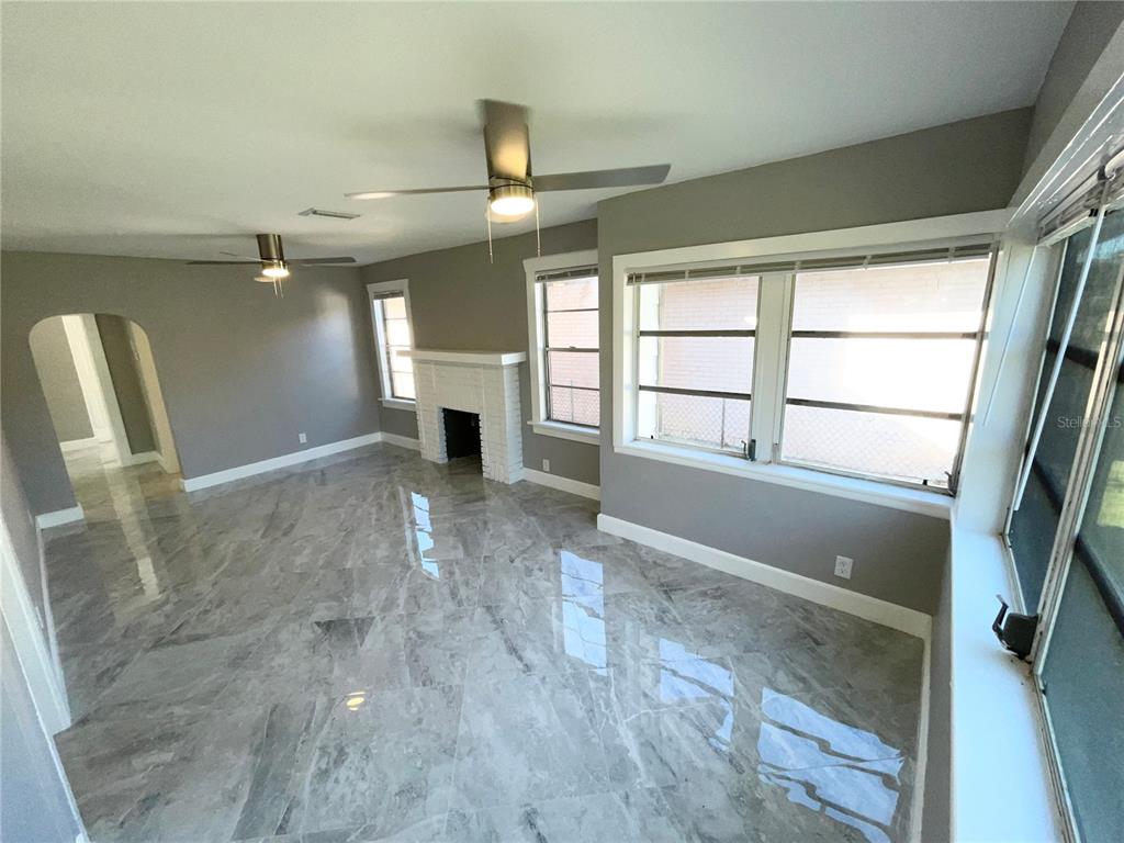 A living room features gray walls, a white fireplace, and polished gray marble-look tile flooring — 2525 37TH STREET S, ST PETERSBURG, FL