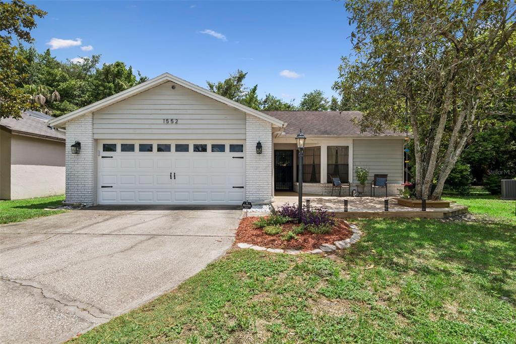 A single-story house with a white brick facade, a two-car garage, and a front patio — 1552 COUGAR COURT, CASSELBERRY, FL
