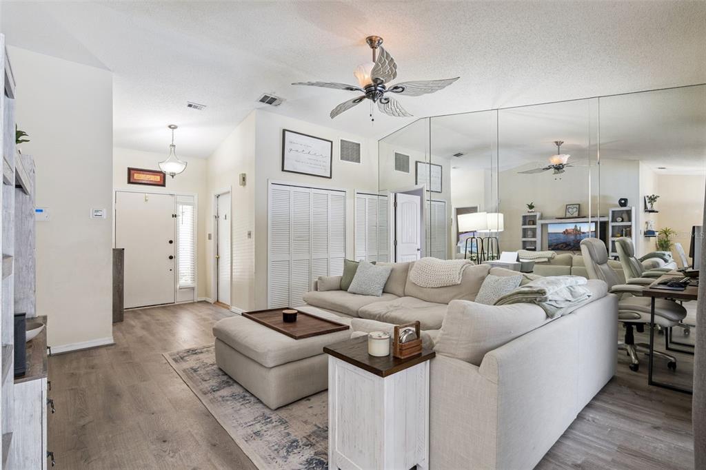 A living room features a large sectional sofa, a mirrored wall, and a ceiling fan — 1552 COUGAR COURT, CASSELBERRY, FL