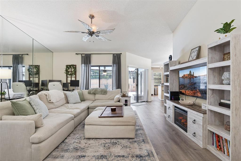 A living room features a large sectional sofa, a fireplace media console, and mirrored walls — 1552 COUGAR COURT, CASSELBERRY, FL