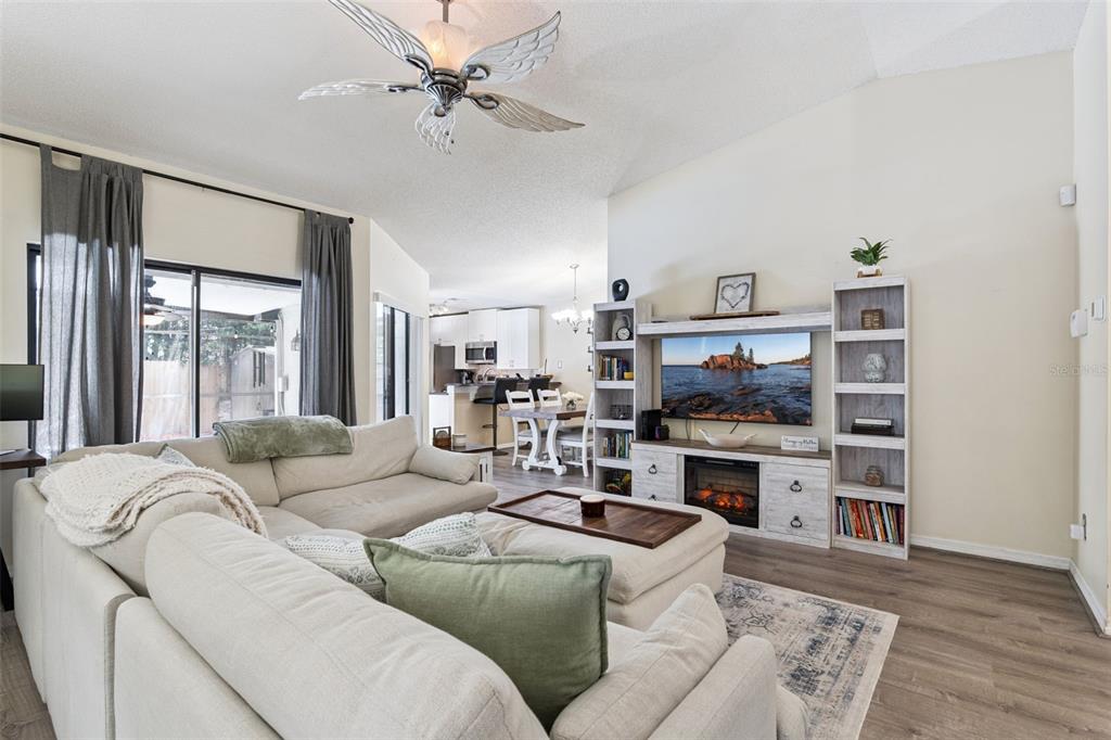 A living room features a sectional sofa, a fireplace media console, and a ceiling fan — 1552 COUGAR COURT, CASSELBERRY, FL