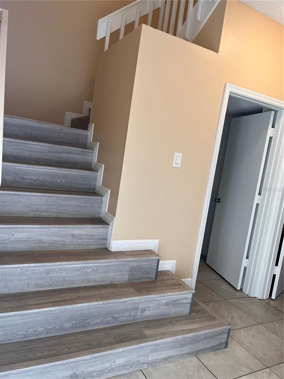 A staircase with wood-look steps leads to a landing beside a bathroom and hallway — 14560 LAGUNA BEACH CIRCLE, ORLANDO, FL