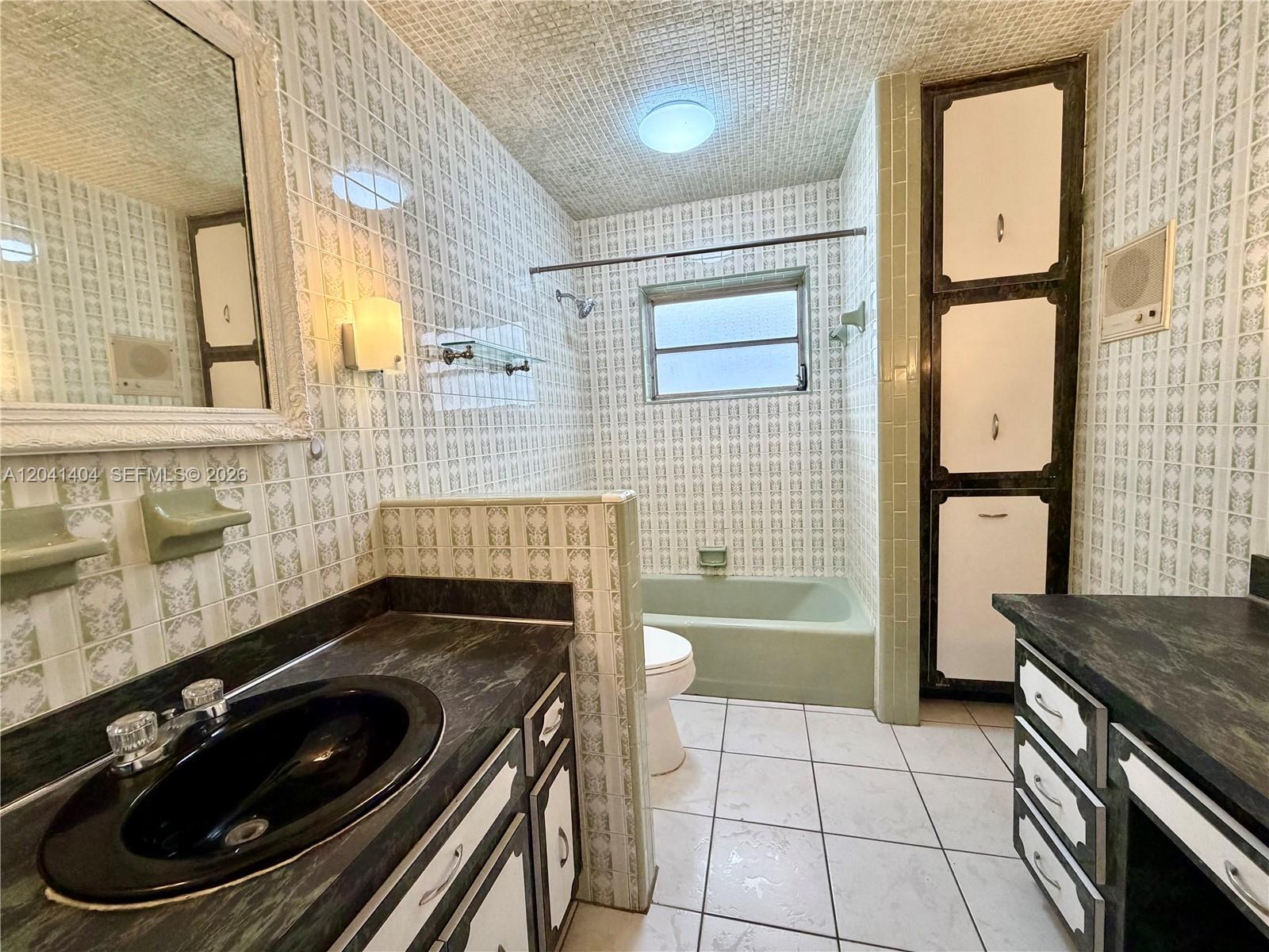 A bathroom features green patterned wall tiles, a dark countertop, and a built-in storage cabinet — 913 NW 22nd Pl # 0, Miami FL 33125, MIAMI, FL
