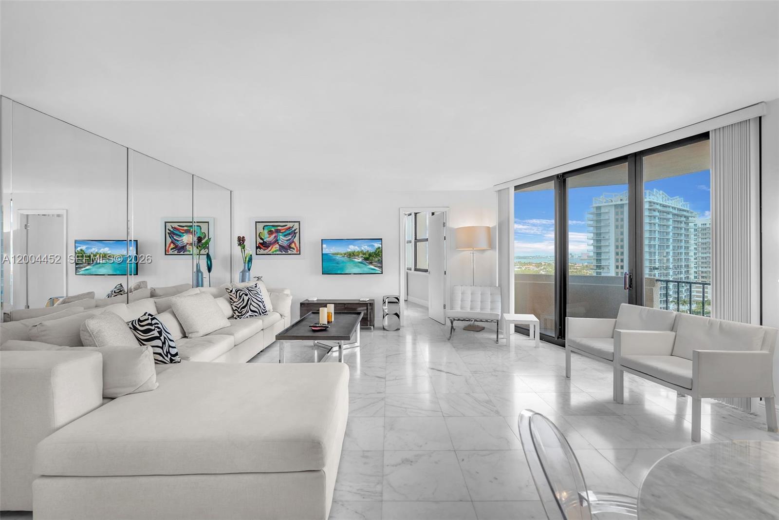 A bright living room features white marble floors, a large sectional sofa, and balcony views — 2800 N Ocean Dr # 15C, Singer Island FL 33404, SINGER ISLAND, FL