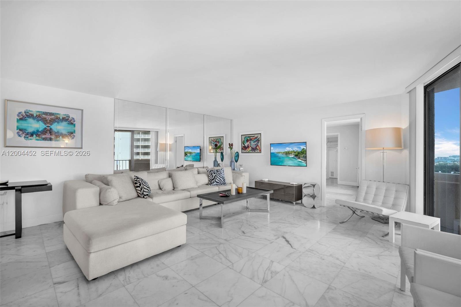 A living room features white marble floors, a large sectional sofa, and mirrored walls — 2800 N Ocean Dr # 15C, Singer Island FL 33404, SINGER ISLAND, FL