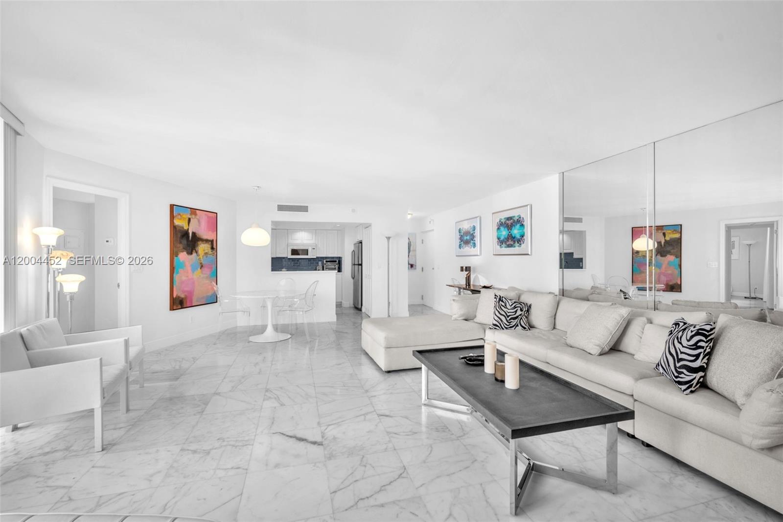 A bright living room features white marble floors, a large sectional sofa, and mirrored walls — 2800 N Ocean Dr # 15C, Singer Island FL 33404, SINGER ISLAND, FL