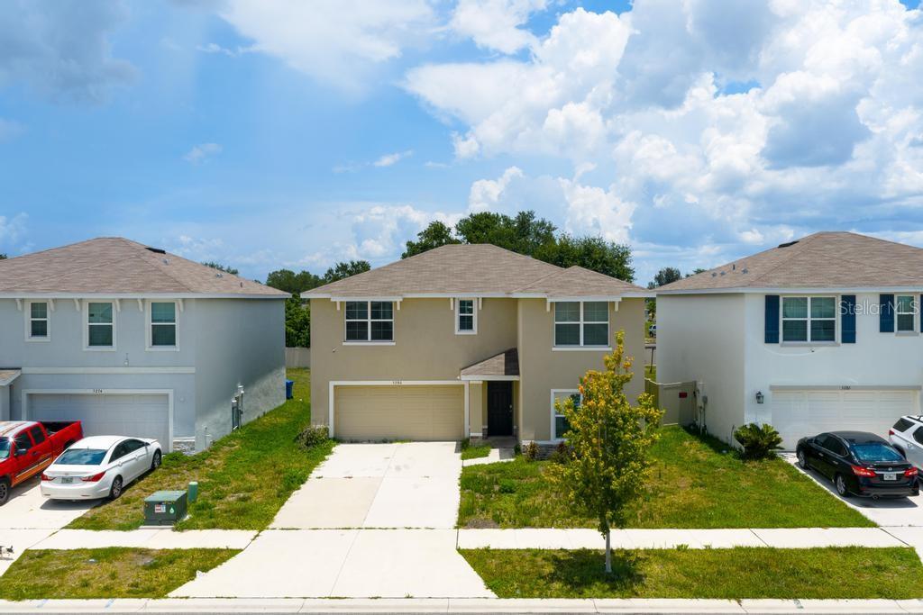 A two-story tan house with a two-car garage and a concrete driveway — 5280 FIDDLE FIG AVENUE, WIMAUMA, FL