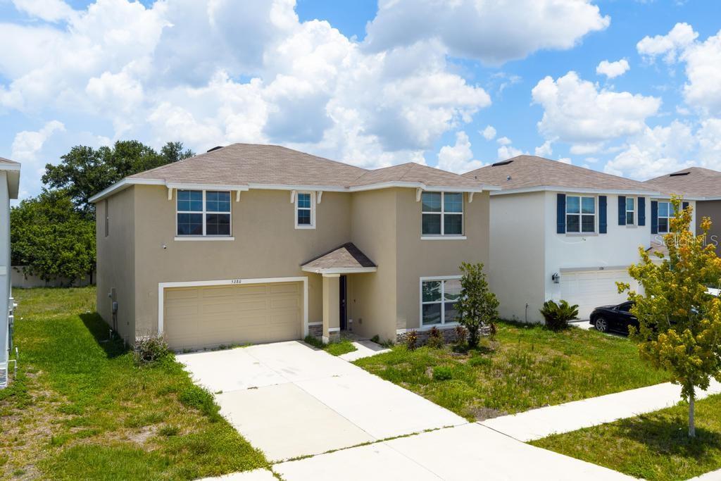 A two-story suburban house with a tan stucco exterior and a two-car garage — 5280 FIDDLE FIG AVENUE, WIMAUMA, FL