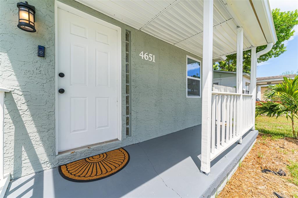 A single-story house with a covered front porch and a white fence under a blue sky — 4651 22ND AVENUE N, ST PETERSBURG, FL