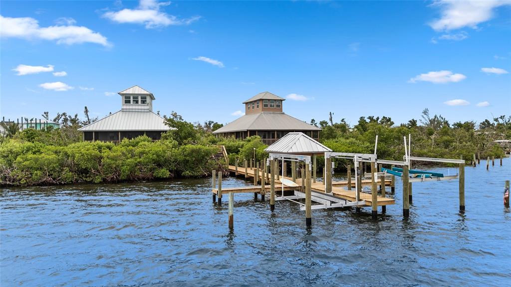 Two houses with metal roofs and a boat dock sit along a mangrove-lined waterfront — 8772 LITTLE GASPARILLA ISLAND, PLACIDA, FL