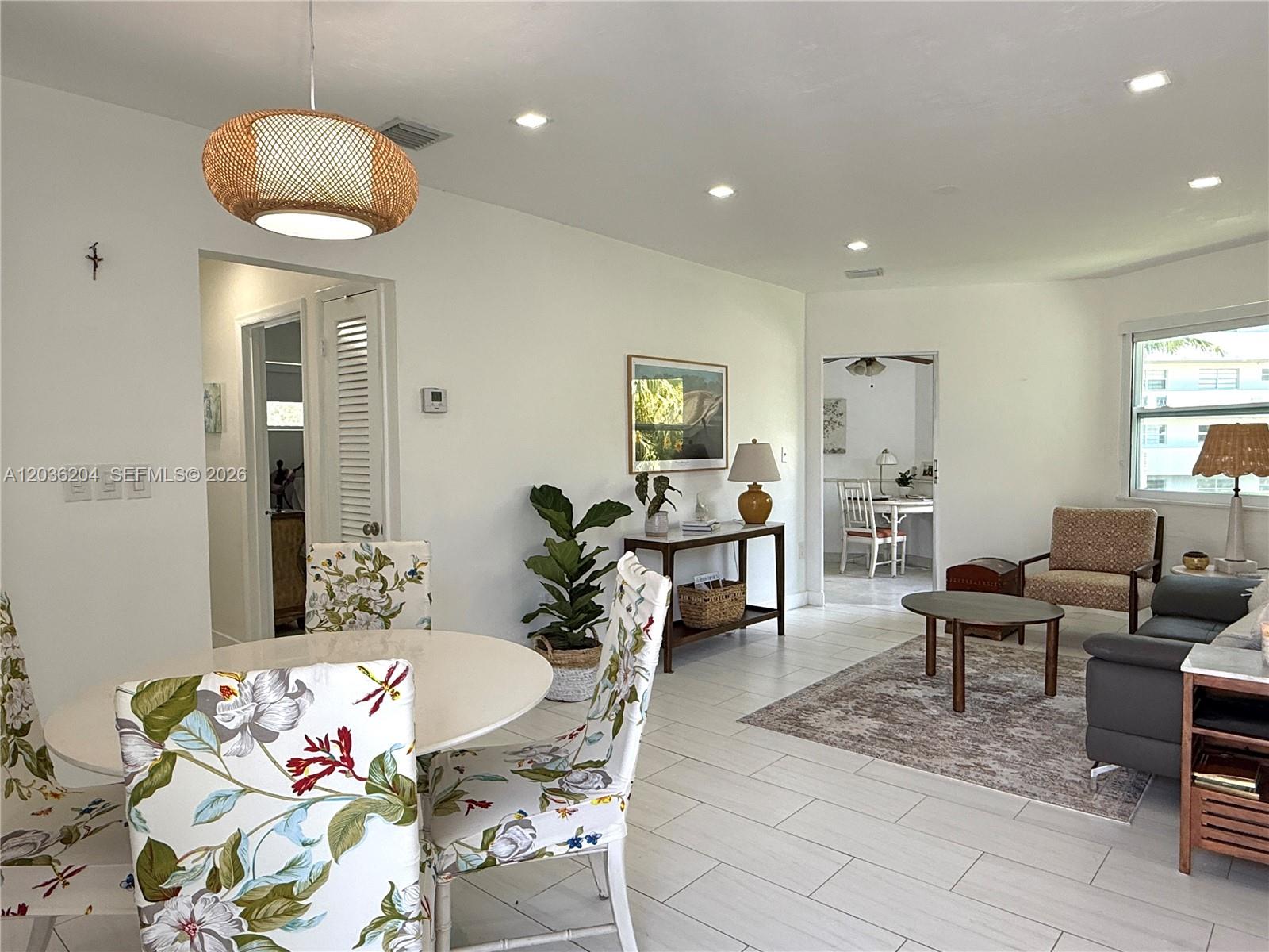 A bright, open-concept living and dining area features white tile floors and floral-patterned chairs — 18750 NE 18th Ave # 251, Miami FL 33179, MIAMI, FL