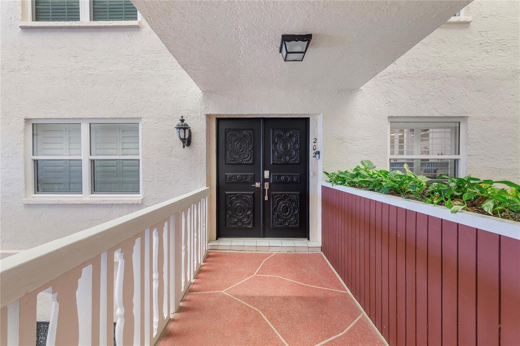 A covered walkway leads to a black double door with decorative panels and house number 202 — 2900 GULF BOULEVARD UNIT 202, BELLEAIR BEACH, FL