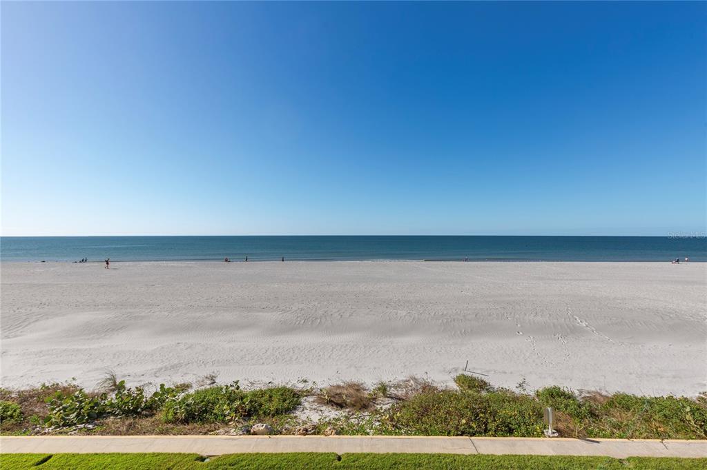 A wide, sandy beach stretches toward the ocean under a clear blue sky — 2900 GULF BOULEVARD UNIT 202, BELLEAIR BEACH, FL