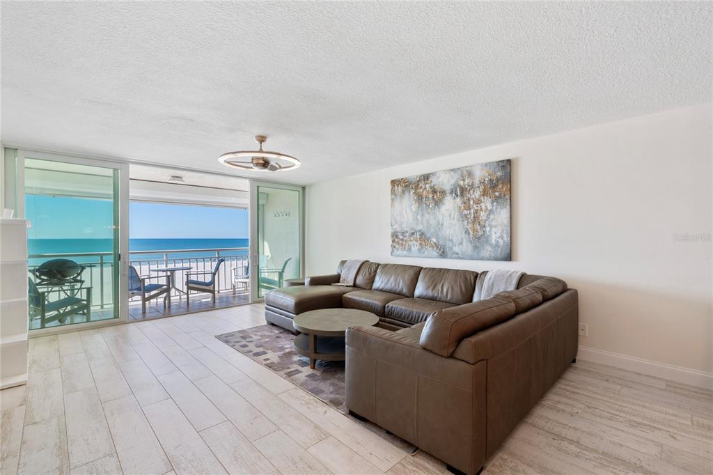 A living room with a brown sectional sofa, area rug, and a balcony overlooking the ocean — 2900 GULF BOULEVARD UNIT 202, BELLEAIR BEACH, FL