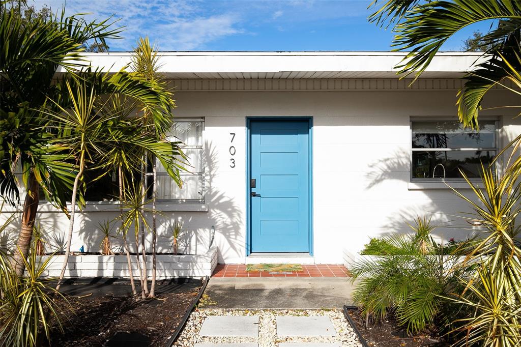 A white house exterior features a bright blue front door and palm trees in front — 703 WHITFIELD AVENUE, SARASOTA, FL