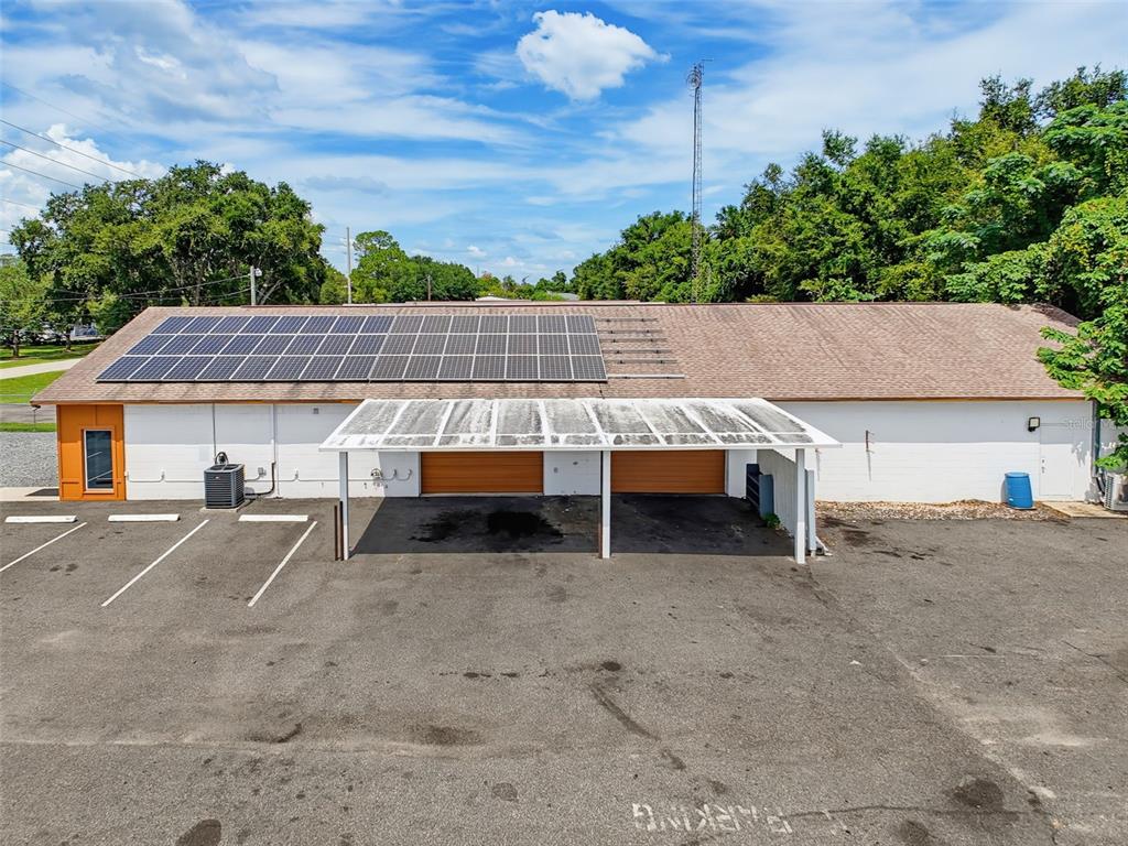 An exterior view of a single-story building with solar panels and a covered parking area — 3347 SW 7TH STREET, OCALA, FL