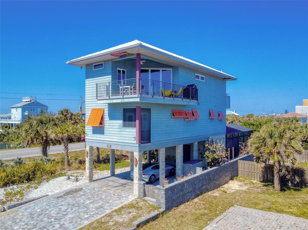 A light blue elevated house with a balcony, orange shutters, and a paved driveway — 901 SHEEPSHEAD AVENUE, NEW SMYRNA BEACH, FL