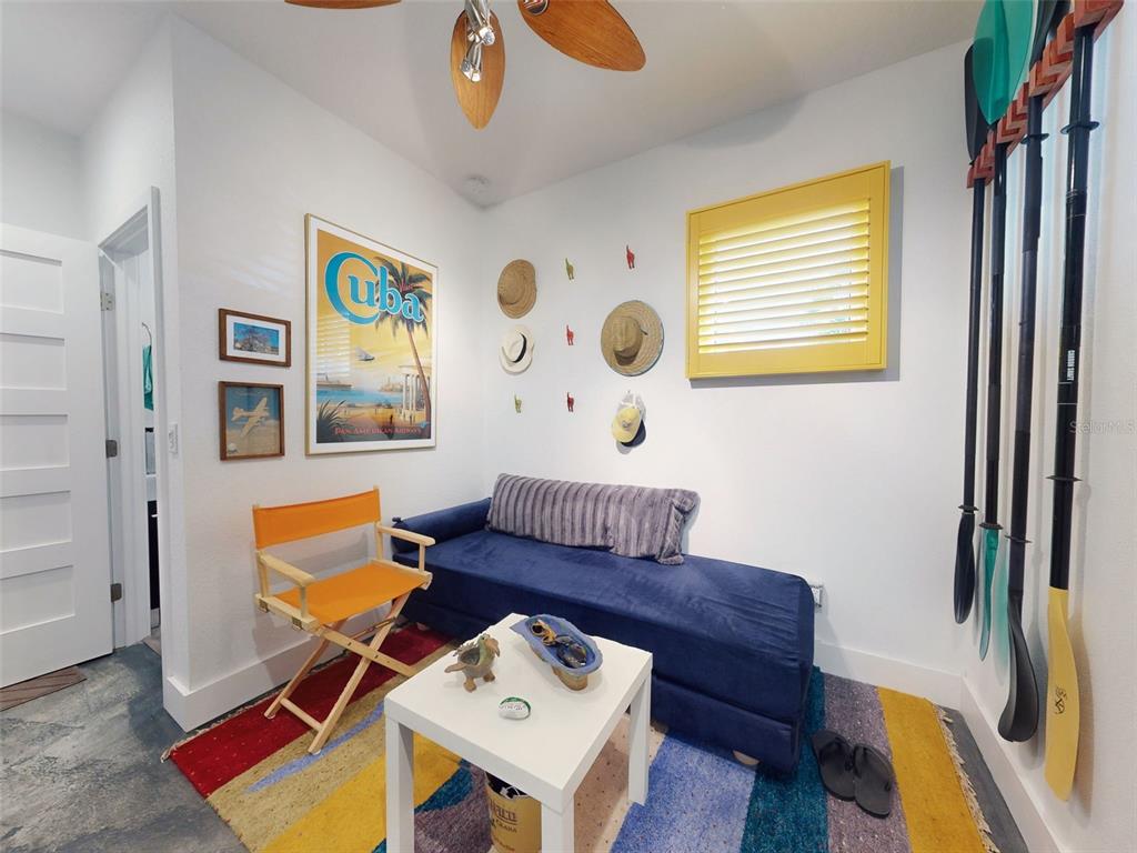 A small room features a blue daybed, an orange director's chair, and wall-mounted paddles — 901 SHEEPSHEAD AVENUE, NEW SMYRNA BEACH, FL