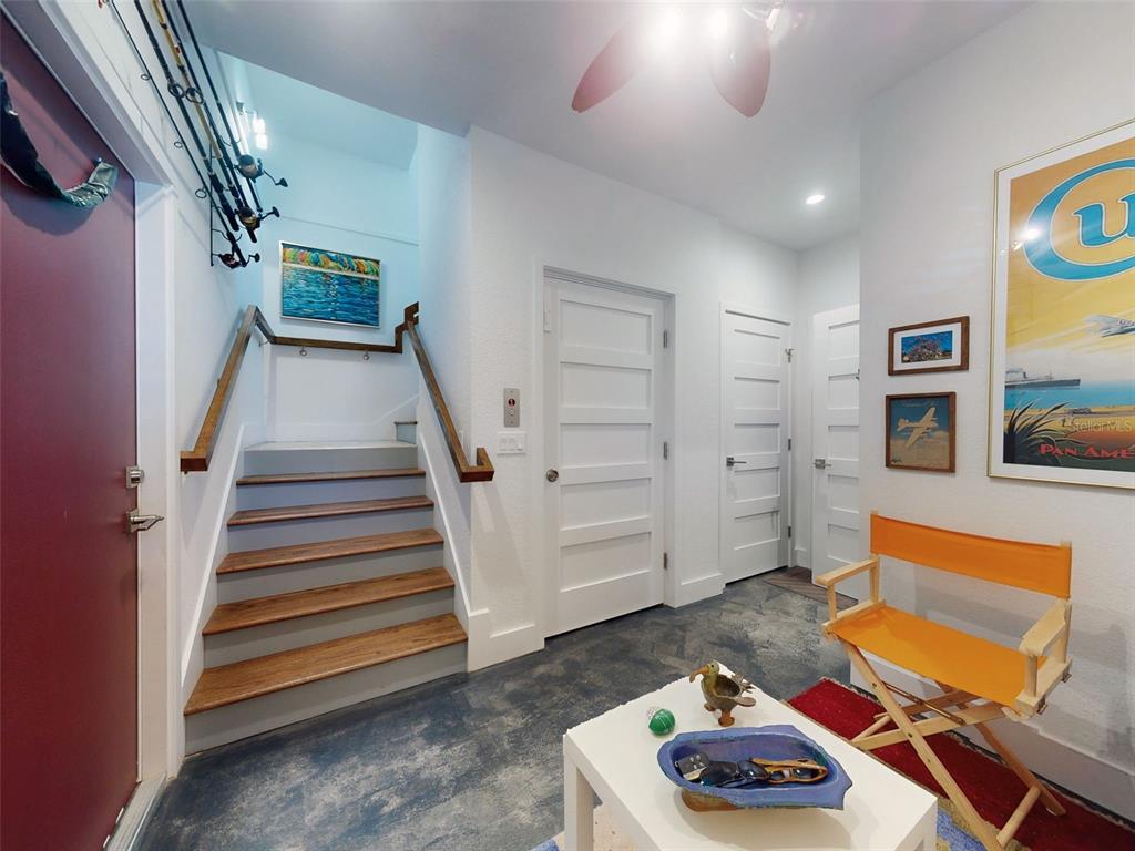 An entryway features a staircase, a white door, a folding chair, and a small table — 901 SHEEPSHEAD AVENUE, NEW SMYRNA BEACH, FL