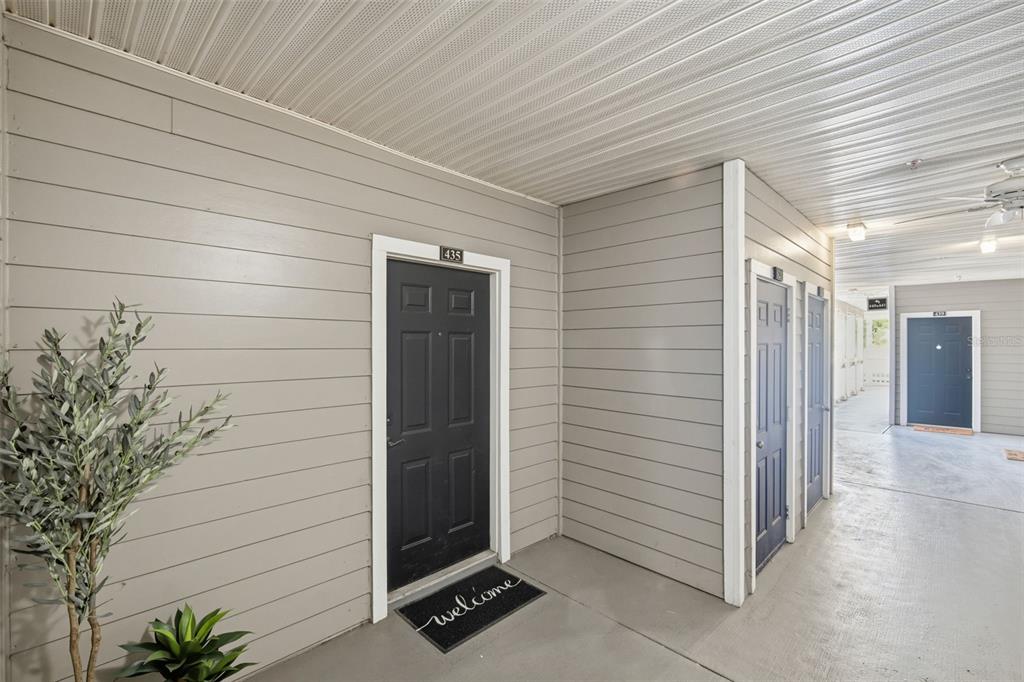 A covered outdoor walkway features light gray horizontal siding and several dark-colored apartment entry doors — 800 S DAKOTA AVENUE UNIT 435, TAMPA, FL
