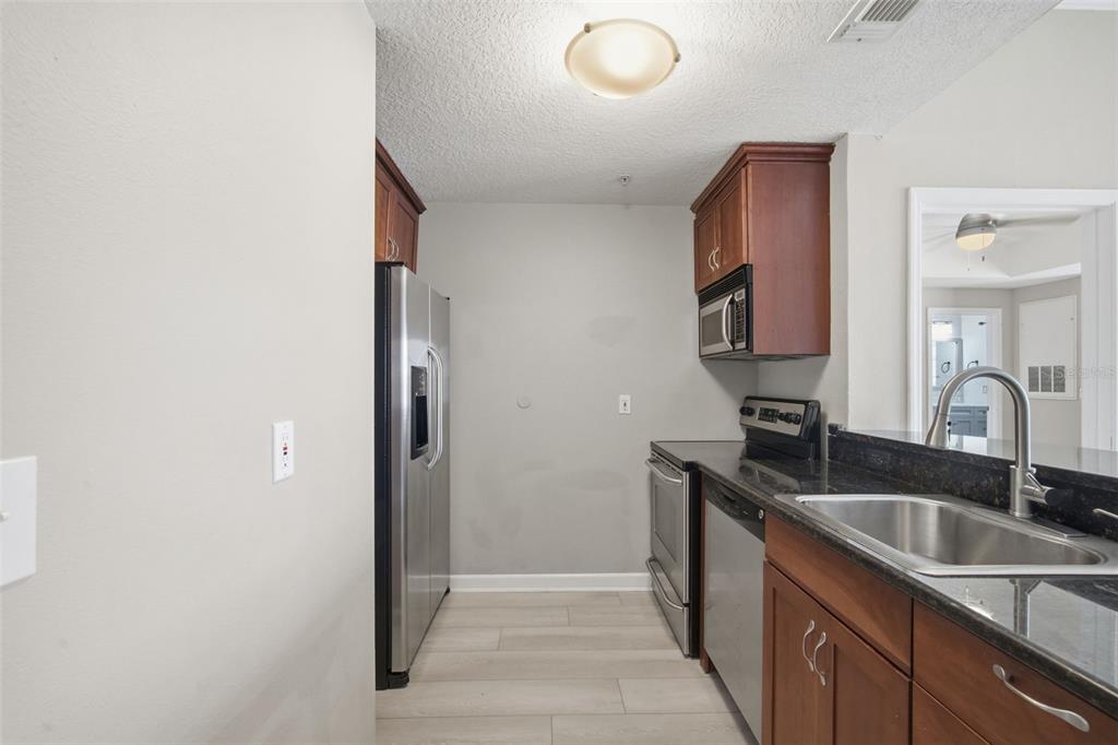 A kitchen features stainless steel appliances, dark wood cabinetry, and granite countertops — 800 S DAKOTA AVENUE UNIT 435, TAMPA, FL