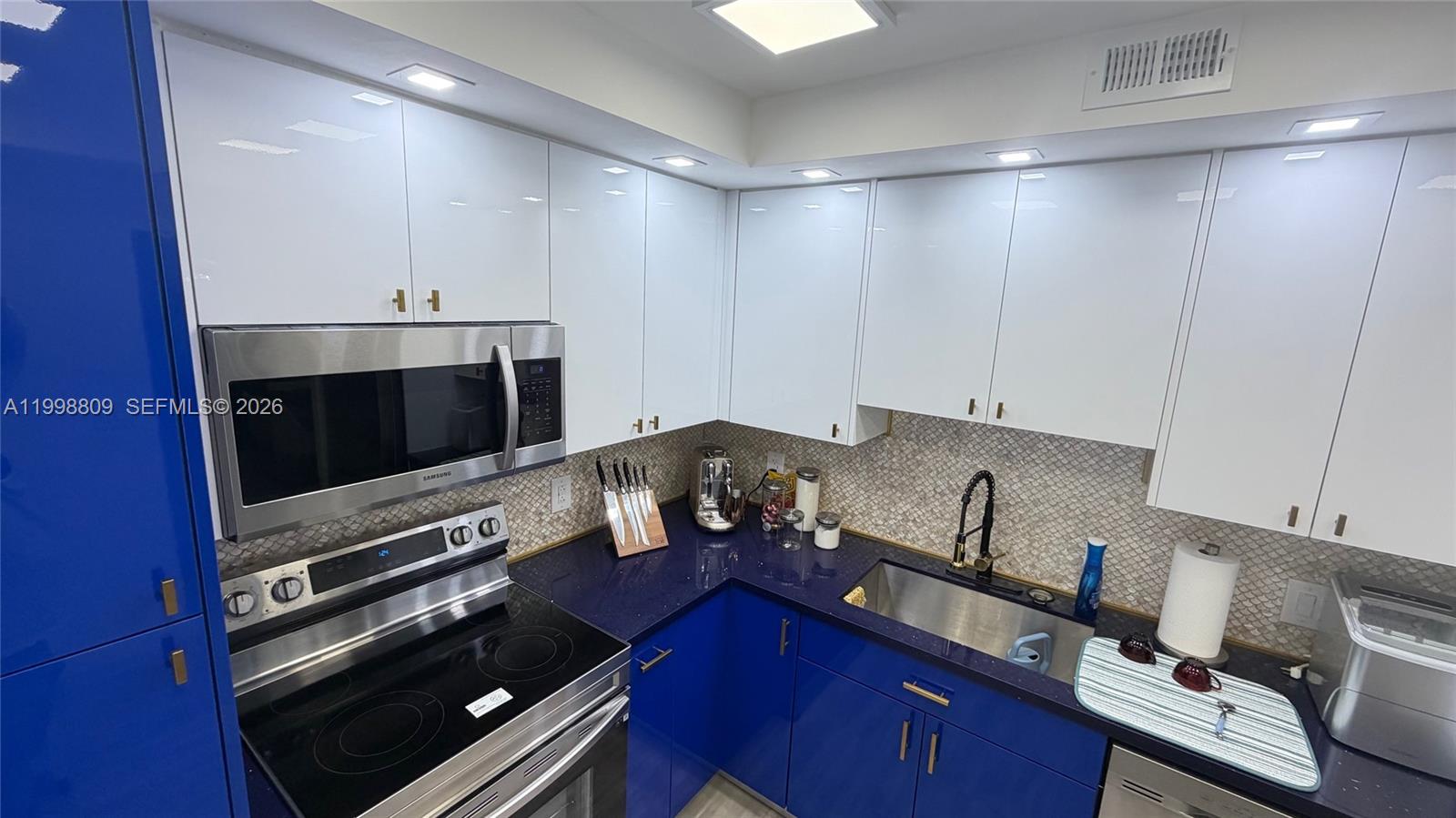 A kitchen features blue lower cabinets, white upper cabinets, and dark blue countertops — 1965 S Ocean Dr # 5D, Hallandale Beach FL 33009, HALLANDALE BEACH, FL