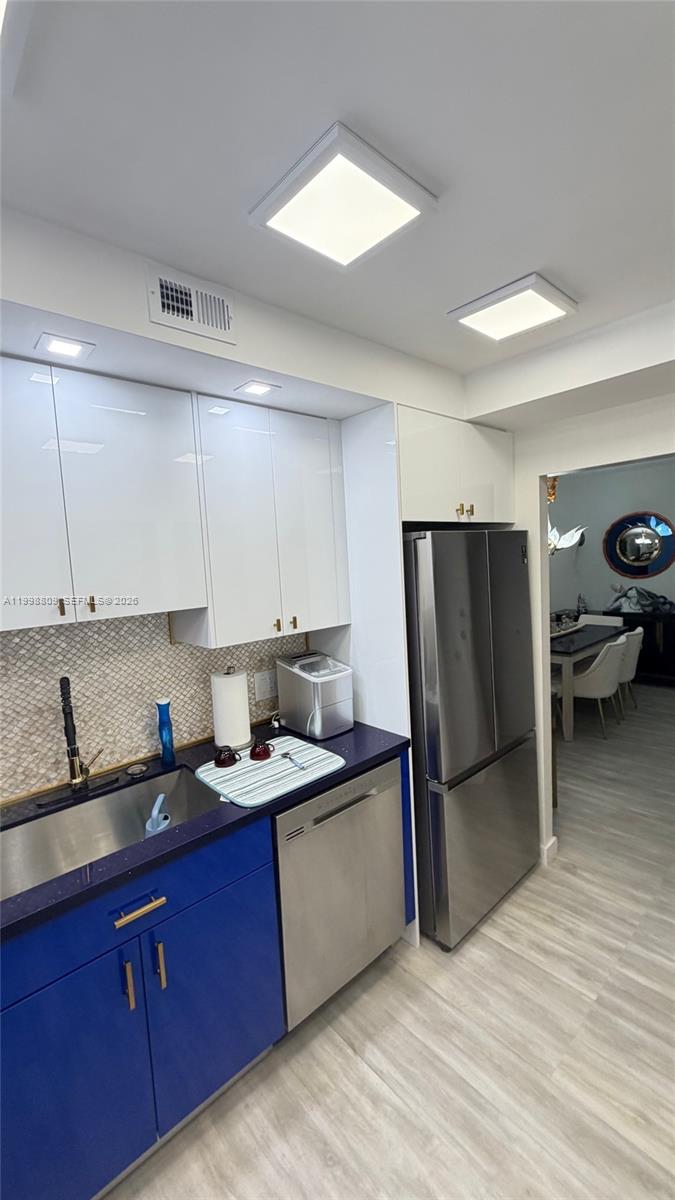 A kitchen features blue lower cabinets, white upper cabinets, stainless steel appliances, and tile backsplash — 1965 S Ocean Dr # 5D, Hallandale Beach FL 33009, HALLANDALE BEACH, FL