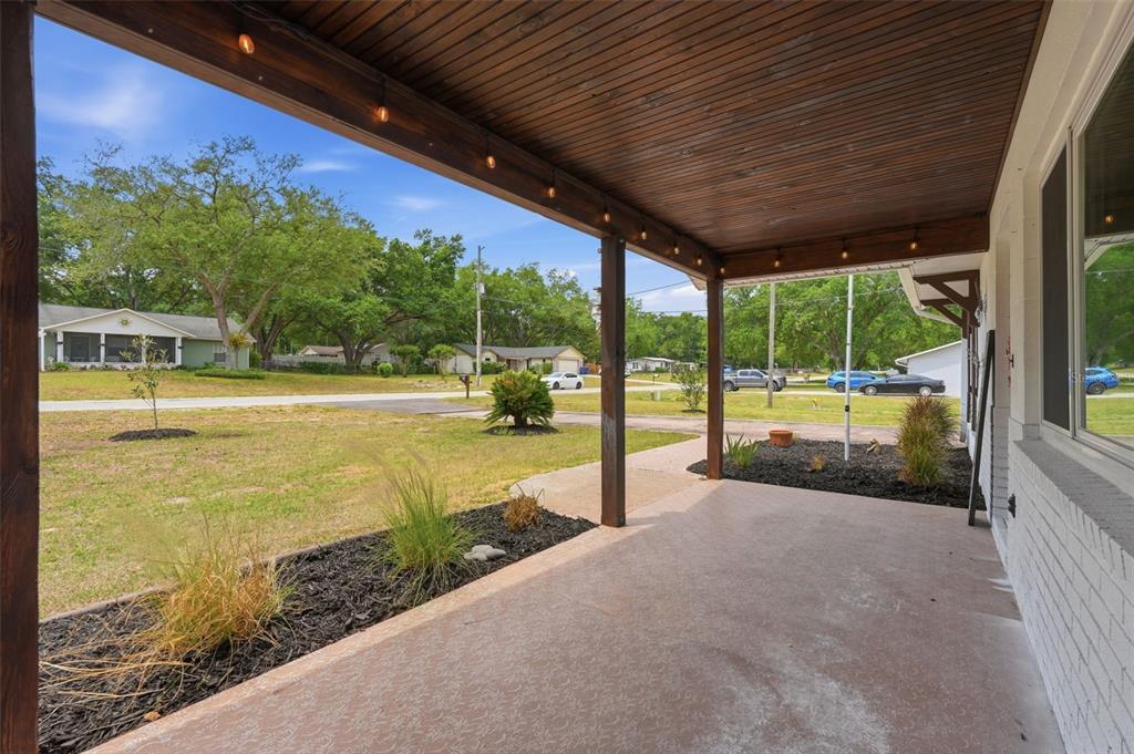 A covered front porch with a wood-plank ceiling, string lights, and a concrete floor — 39825 SUNBURST DRIVE, DADE CITY, FL