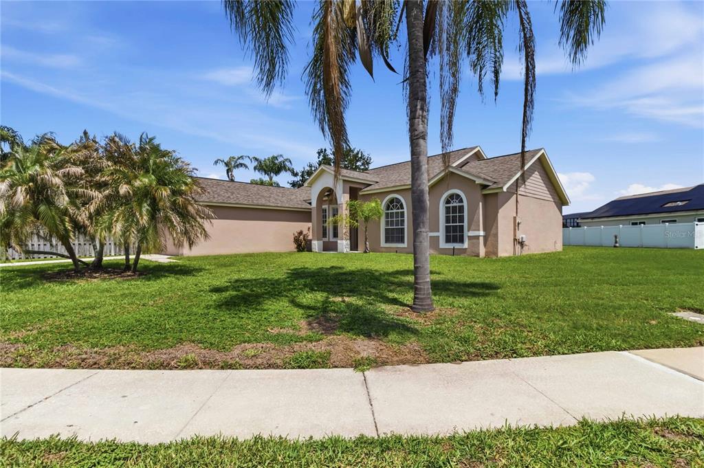 A single-story tan house with a palm tree in the front yard — 1019 CHAMBERLIN TRAIL, ST CLOUD, FL
