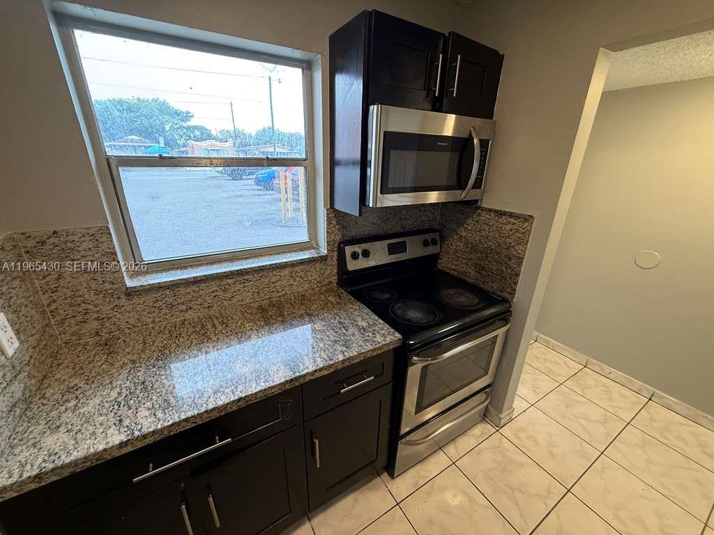 A kitchen features dark cabinets, granite countertops, stainless steel appliances, and a window — 2721 NW 23rd Ct # 4, Miami FL 33142, MIAMI, FL