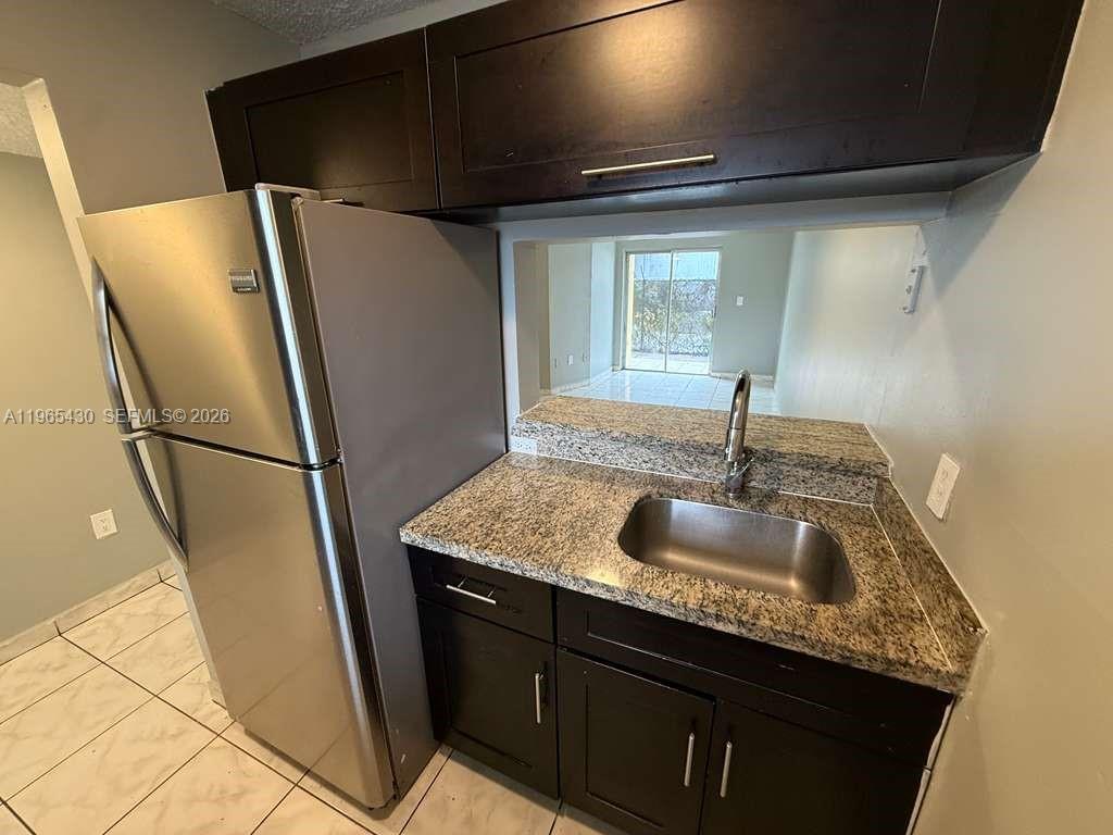 A kitchen features dark wood cabinets, granite countertops, a stainless steel sink, and a refrigerator — 2721 NW 23rd Ct # 4, Miami FL 33142, MIAMI, FL