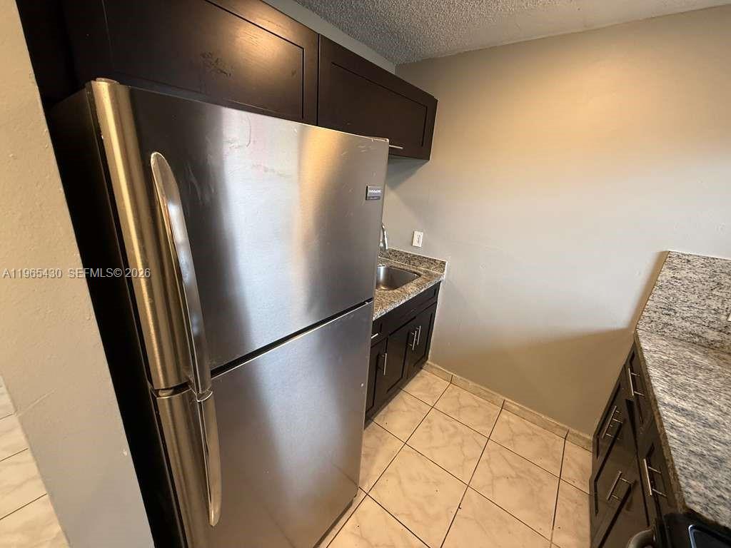 A kitchen features dark wood cabinets, granite countertops, stainless steel appliances, and light tile flooring — 2721 NW 23rd Ct # 4, Miami FL 33142, MIAMI, FL