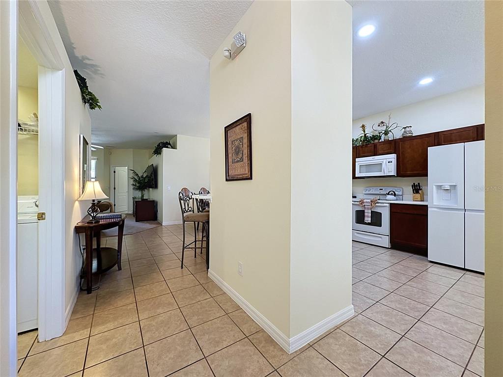 A view from a tiled hallway looking toward a kitchen and an adjacent living area — 906 DORSET PLACE, DAVENPORT, FL
