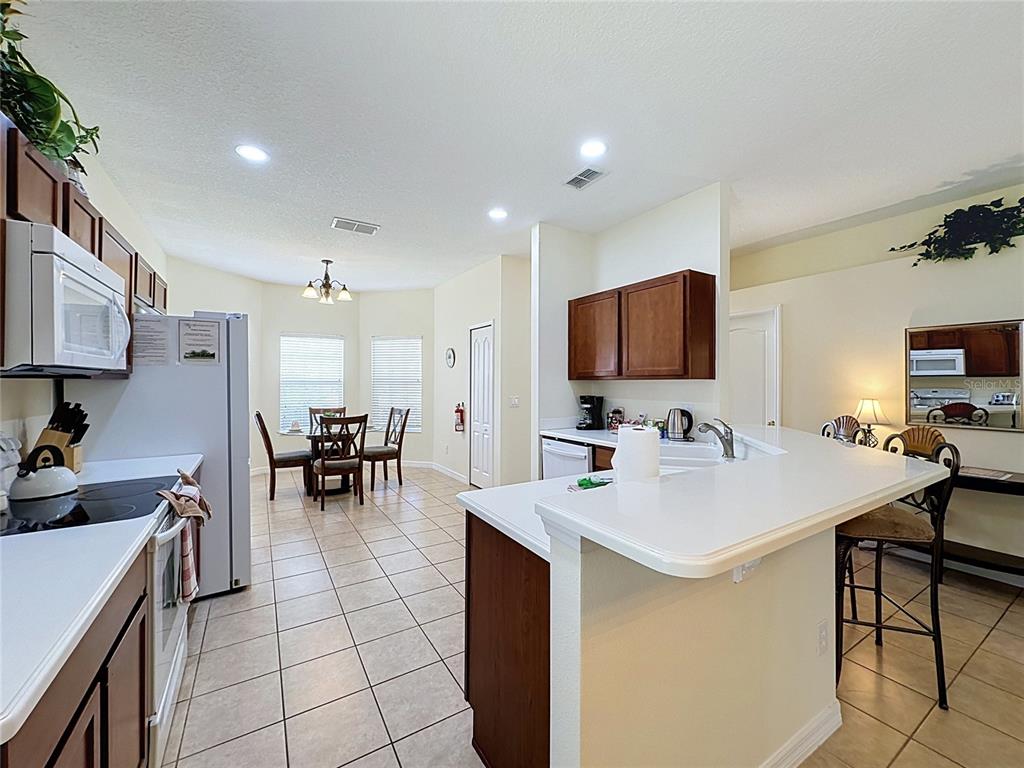A kitchen with white countertops, dark wood cabinets, and a dining area with tile floors — 906 DORSET PLACE, DAVENPORT, FL