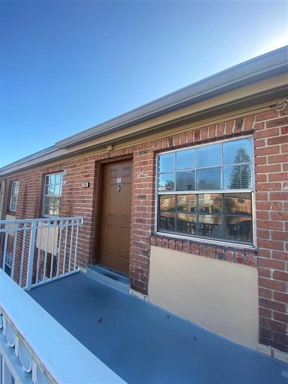 An exterior view of a brick building featuring a balcony, a brown door, and windows — 551 FLEMMING WAY UNIT 201, MAITLAND, FL