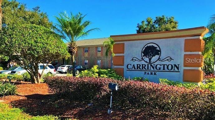A large sign for Carrington Park stands in front of a multi-story brick apartment building — 551 FLEMMING WAY UNIT 201, MAITLAND, FL