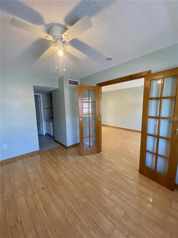 A room with light-colored walls, wood flooring, a ceiling fan, and French doors — 551 FLEMMING WAY UNIT 201, MAITLAND, FL