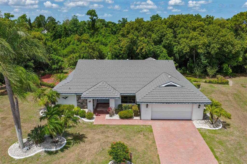 An aerial view of a single-story house with a gray tile roof and brick driveway — 1819 NEW BEDFORD DRIVE, SUN CITY CENTER, FL