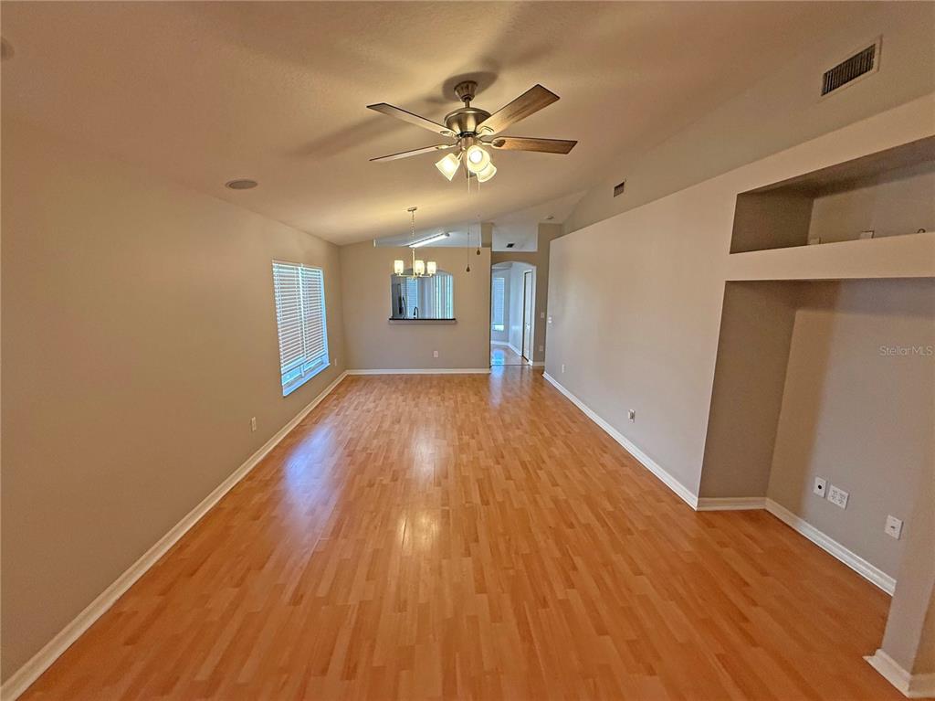 An empty living room features light wood flooring, a ceiling fan, and beige walls — 10608 NAVIGATION DRIVE, RIVERVIEW, FL