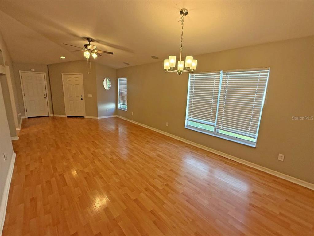 A living room features light hardwood floors, a ceiling fan, and a dining chandelier — 10608 NAVIGATION DRIVE, RIVERVIEW, FL