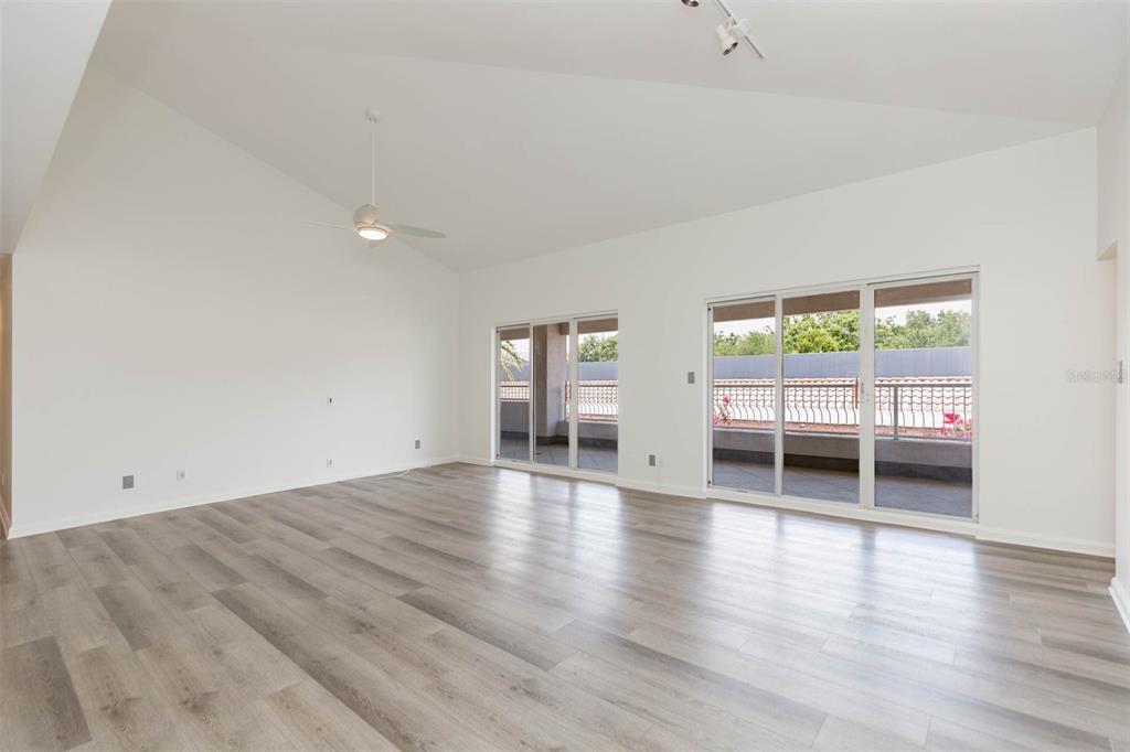 An empty living room with vaulted ceilings, a ceiling fan, and light wood-look flooring — 1653 W SNOW CIRCLE UNIT 1653, TAMPA, FL