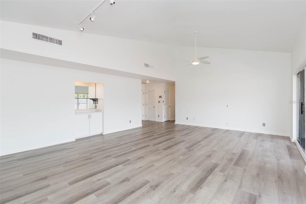 A spacious living room features vaulted ceilings, light wood-look flooring, and a small wet bar — 1653 W SNOW CIRCLE UNIT 1653, TAMPA, FL