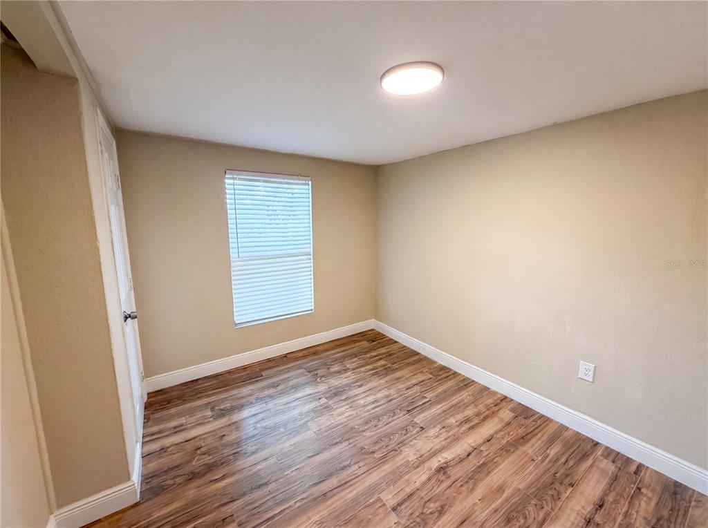 An empty bedroom features light-colored walls, wood-look flooring, a single window, and a ceiling light — 1506 W 16TH STREET, SANFORD, FL