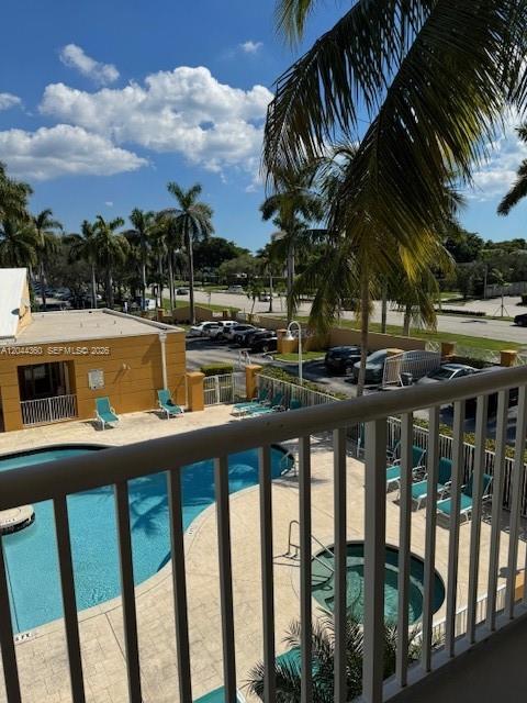 A balcony view overlooks a swimming pool, hot tub, and parking lot with palm trees — 1450 SE 3rd Ave # 302, Dania Beach FL 33004, DANIA BEACH, FL