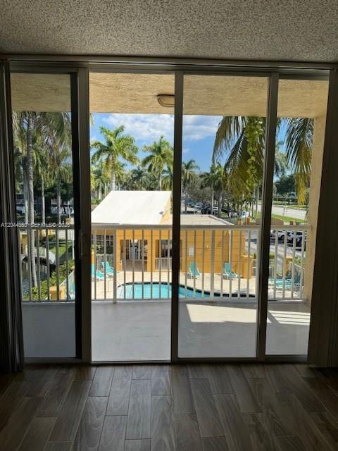 A view from inside through sliding glass doors looking out onto a pool and palm trees — 1450 SE 3rd Ave # 302, Dania Beach FL 33004, DANIA BEACH, FL