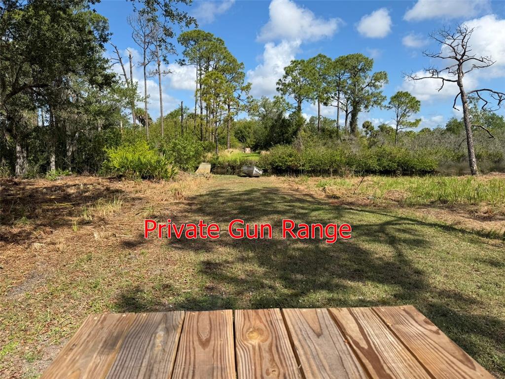 An outdoor area features a wooden table in the foreground overlooking a grassy shooting range — 1213 CASPER STREET, PORT CHARLOTTE, FL