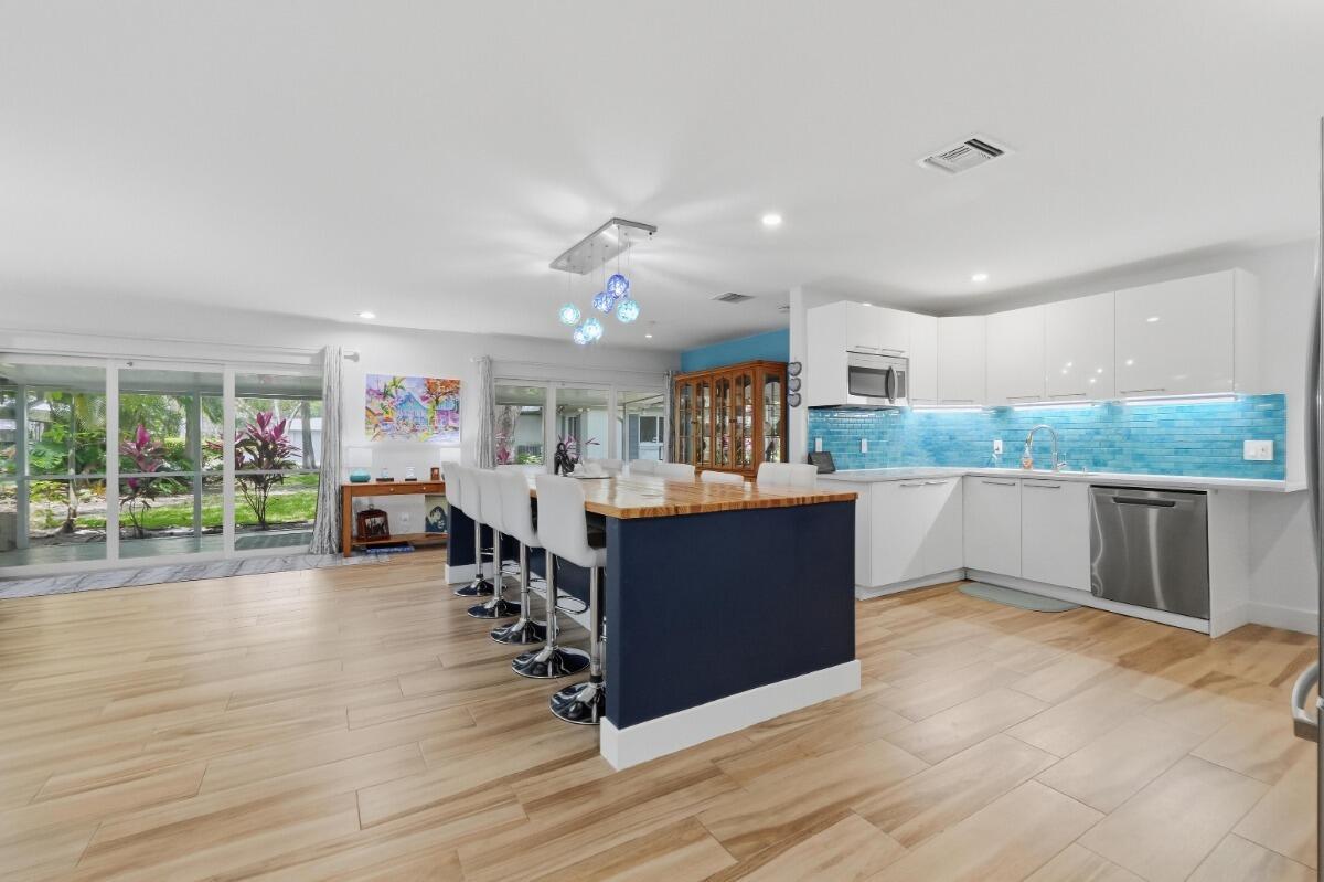 A kitchen with a dark blue island, white cabinets, and a bright blue tile backsplash — 904 W Cypress Lane # 46, Pompano Beach FL 33069, POMPANO BEACH, FL