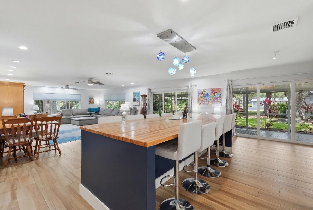 A kitchen island with a wood countertop and bar stools sits in an open-concept room — 904 W Cypress Lane # 46, Pompano Beach FL 33069, POMPANO BEACH, FL