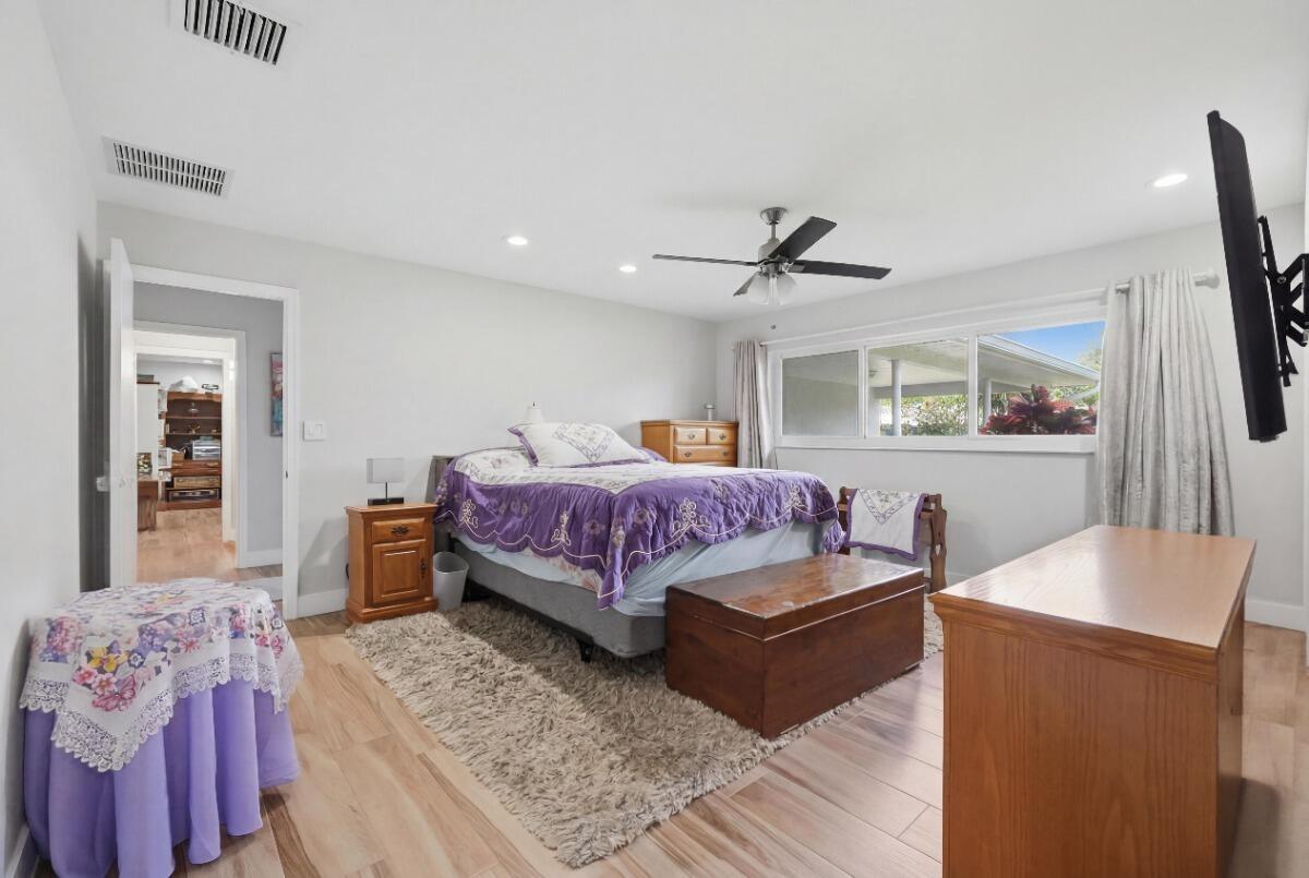 A bedroom features light wood flooring, a purple bedspread, a ceiling fan, and a window — 904 W Cypress Lane # 46, Pompano Beach FL 33069, POMPANO BEACH, FL