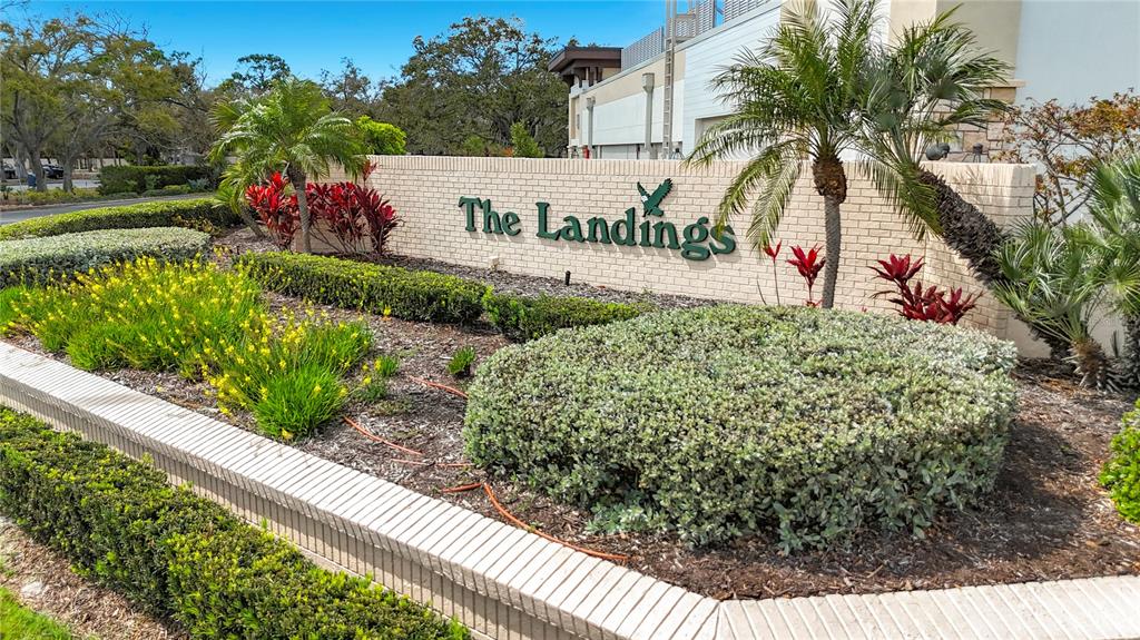 A brick wall sign reading The Landings sits in a landscaped garden with palm trees — 1445 LANDINGS CIRCLE UNIT 69, SARASOTA, FL